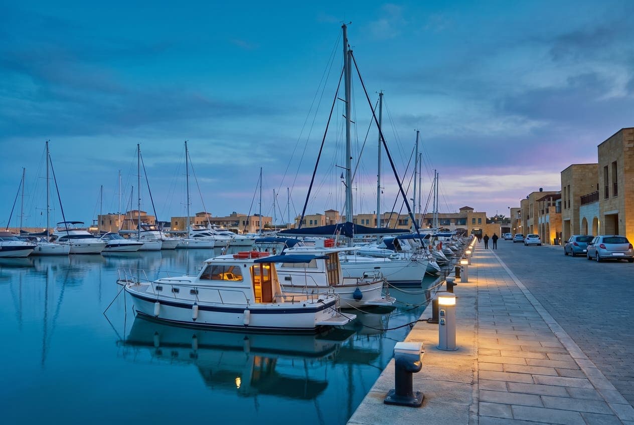 Marina with yachts at their berths and low buildings along the quay