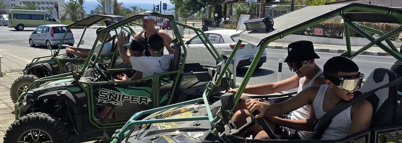 Riders in sunglasses seated in green buggies parked at a roadside